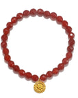 The Red Carnelian Mandala Bracelet consists of round, faceted red beads and showcases a gold circular pendant adorned with an intricate sunburst design. This gemstone bracelet is perfectly arranged in a circle, capturing the essence of healing jewelry.