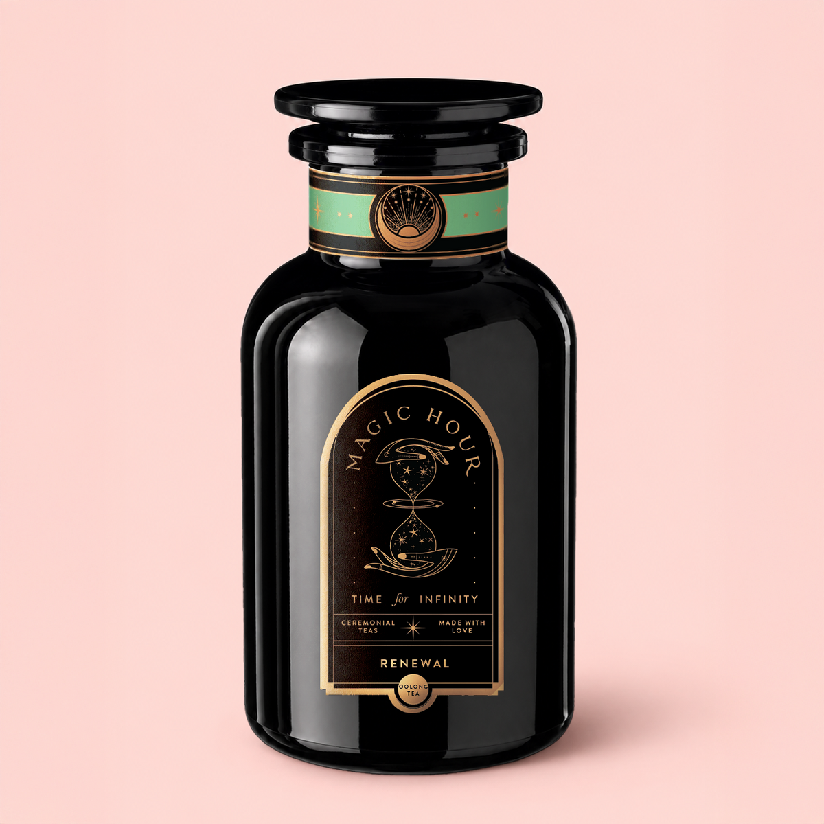 A black glass tea jar labeled “Renewal: Peach-Goji-Rose Oolong Tea” with gold and teal accents, adorned with celestial graphics and a round lid. Set against a light pink background, it evokes the lush notes of Oolong tea infused with hints of peach, creating an enchanting tea experience.