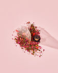 A Tea for Beauty: Renewal: Peach, Goji & Rose Oolong Tea pyramid bag resting on a pile of loose-leaf peach oolong tea, dried rose petals, and goji berries.
