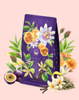 A purple tea bag adorned with illustrations of passion fruit, vanilla, and delicate flowers is surrounded by tea leaves, blossoms, and fresh passion fruit on a pastel pink background. This vibrant scene evokes the enchanting essence of Romance in Ravello—a Chocolate-Passionfruit-Rose-Cream White Tea inspired by the romance of the Amalfi Coast.