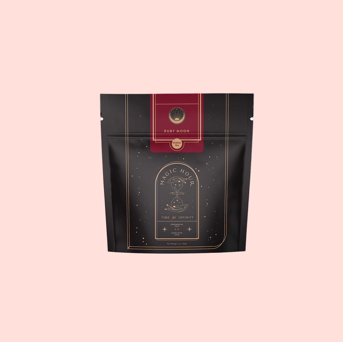 A black and gold resealable pouch labeled "Magic Hour" with a red top that says "Ruby Moon™ Herbal Tea Bags." The elegant celestial design highlights this caffeine-free hibiscus tea against a plain light gray background.