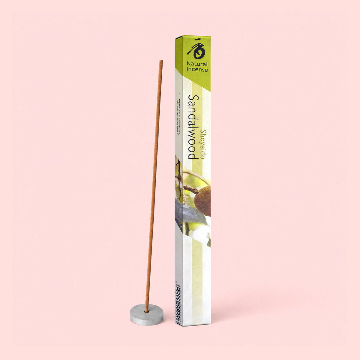 A box of Natural Incense: Sandalwood, crafted from pure ingredient blends, stands upright beside a single incense stick placed in a small round holder, all set against a light pink background. The earthy sandalwood fragrance gently infuses the scene with calm and warmth.