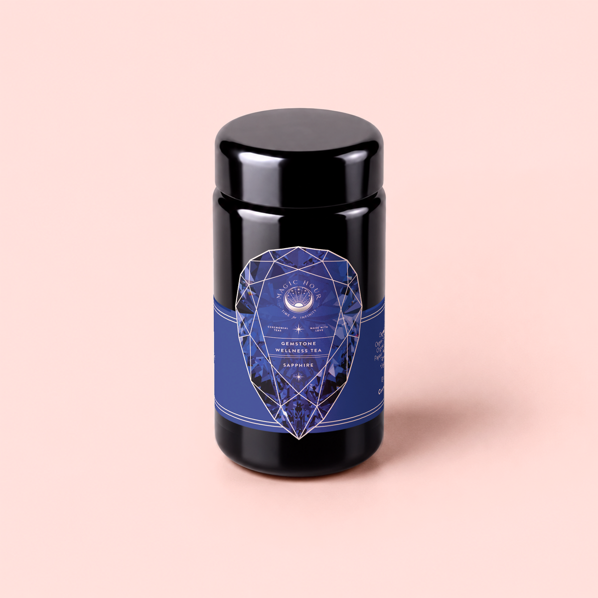 A dark jar with a blue geometric label reading “Sapphire: Apple-Plum-Spice White Tea for Self-Expression” is set against a light pink background, inviting you to experience the soothing elegance of this premium organic blend designed to inspire self-expression.