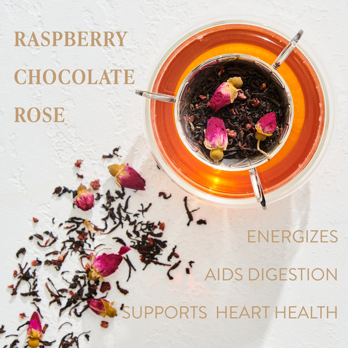 A glass cup of tea with loose leaf tea leaves, rose petals, and a tea infuser sits on a white surface. The tea is a rosy-brown color. Text around the image reads: "SOULMATE: CHOCOLATE-RASPBERRY-ROSE BLACK TEA FOR FINDING & CELEBRATING LOVE," "ENERGIZES," "AIDS DIGESTION," and "SUPPORTS HEART HEALTH." Experience the magic hour with organic tea bliss from Magic Hour.