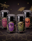 Four jars of the Spellbound Sips Bundle tea, featuring labels with mystical themes like a black cat, ravens, hibiscus, and candy corn, arranged against a dark background with gold illustrations of insects and stars.