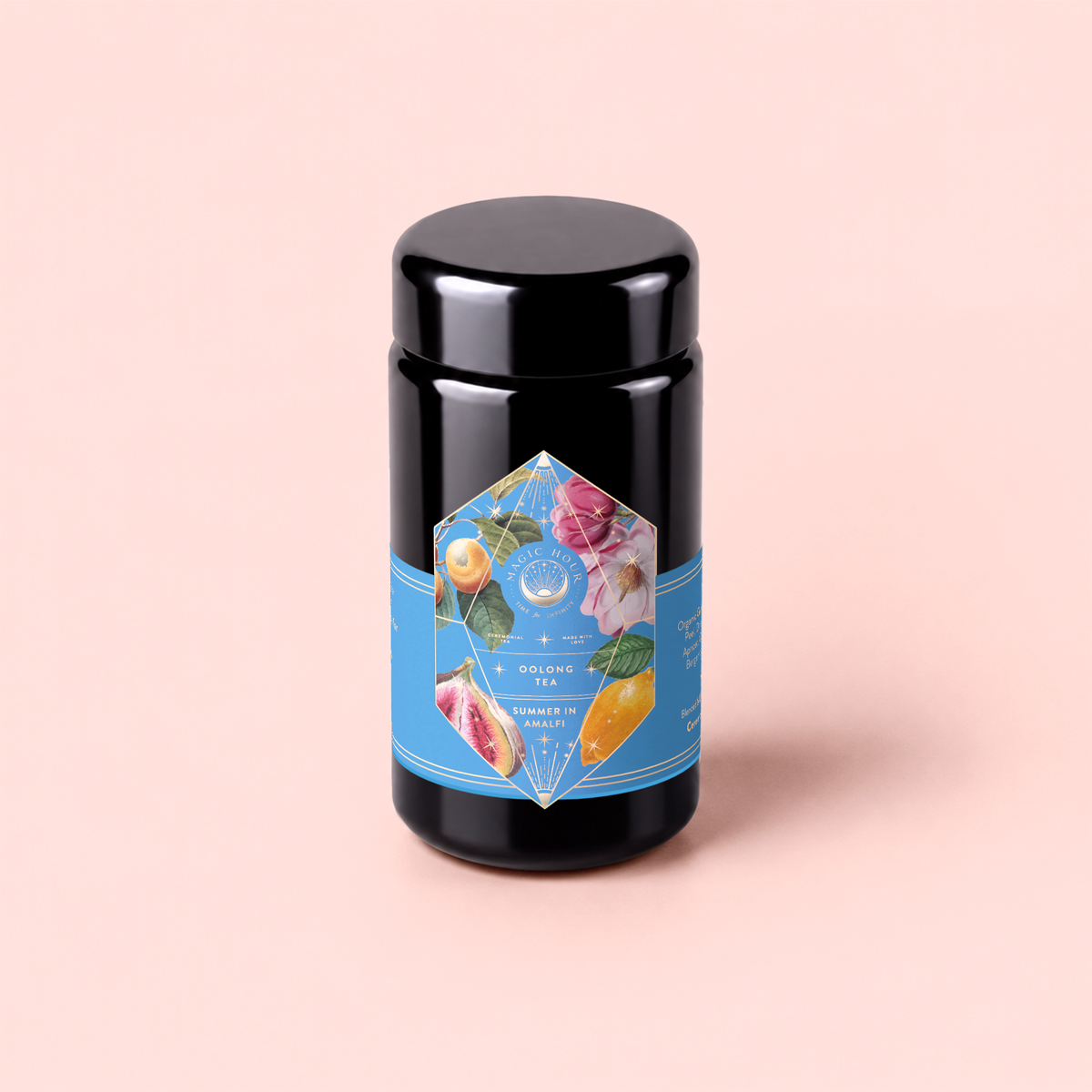 Summer in Amalfi is a black tea canister adorned with a blue label featuring vibrant fruit and floral illustrations, set against a light pink background—this charming tin evokes the refreshing flavors of Amalfi Coast tea, with notes of lemon bergamot and delicate organic oolong.