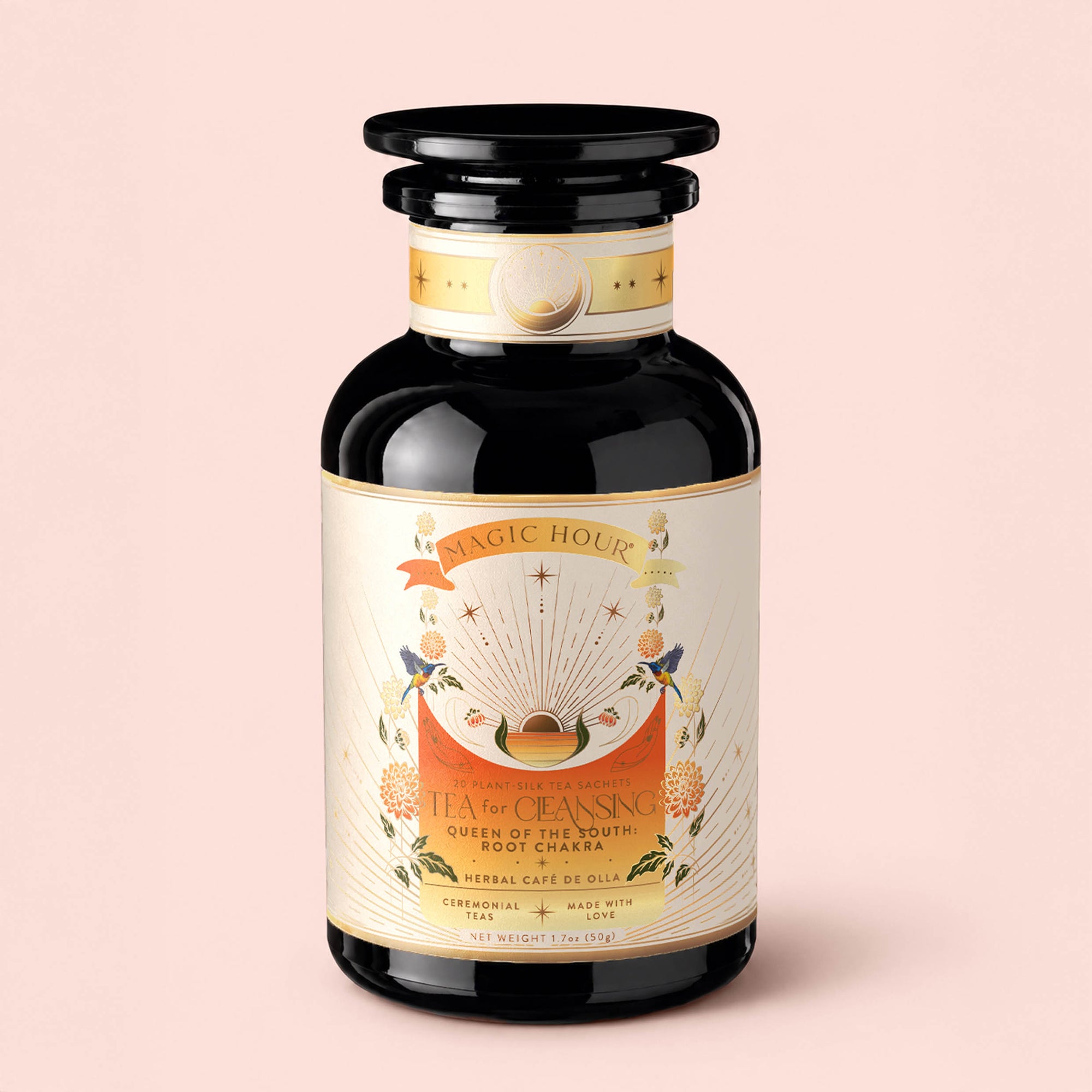 A dark glass jar labeled "Tea for Cleansing: Queen of the South: Herbal Cafe de Olla," adorned with decorative floral and celestial designs, sits against a pale pink background. This antioxidant-rich, caffeine-free Cocoa Detox Tea exudes an aura of purity and indulgence.