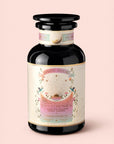 A glass jar of Magic Hour’s "Tea for Compassion: Ti Quan Yin: Organic Oolong Tea," adorned with pink, gold, and white celestial-themed artwork, containing organic oolong tea sachets.