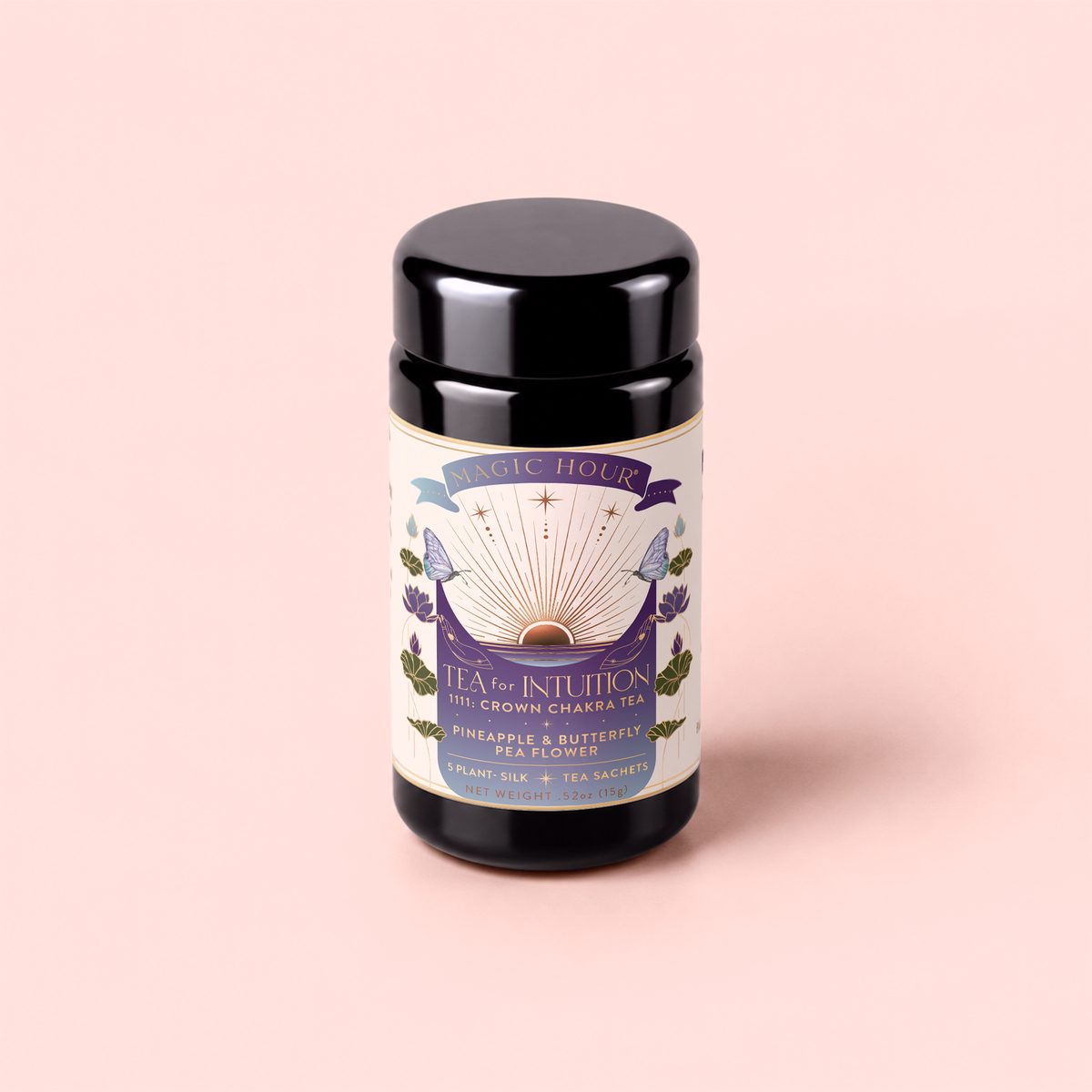 A black canister of “Tea for Intuition: 1111: Pineapple & Butterfly Pea Flower Herbal Tea” with purple and gold details is set against a pale pink background. The label features ingredients such as pineapple, butterfly pea flower, and delicate blue lotus to support your crown chakra connection, and notes the inclusion of plant-silk tea sachets.