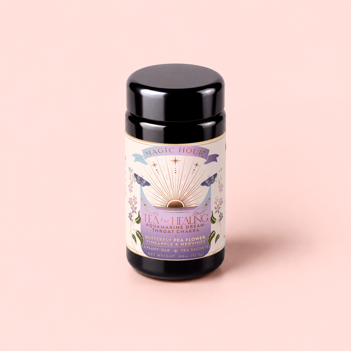A canister of Tea for Healing: Aquamarine Dream—Blueberries, Pineapple & Nervines Herbal Tea—stands on a pastel pink background. The label showcases botanical illustrations, colorful details, and highlights the presence of butterfly pea flowers alongside notes of pineapple. This adaptogenic blend is carefully crafted to support the nervous system and promote overall wellness.