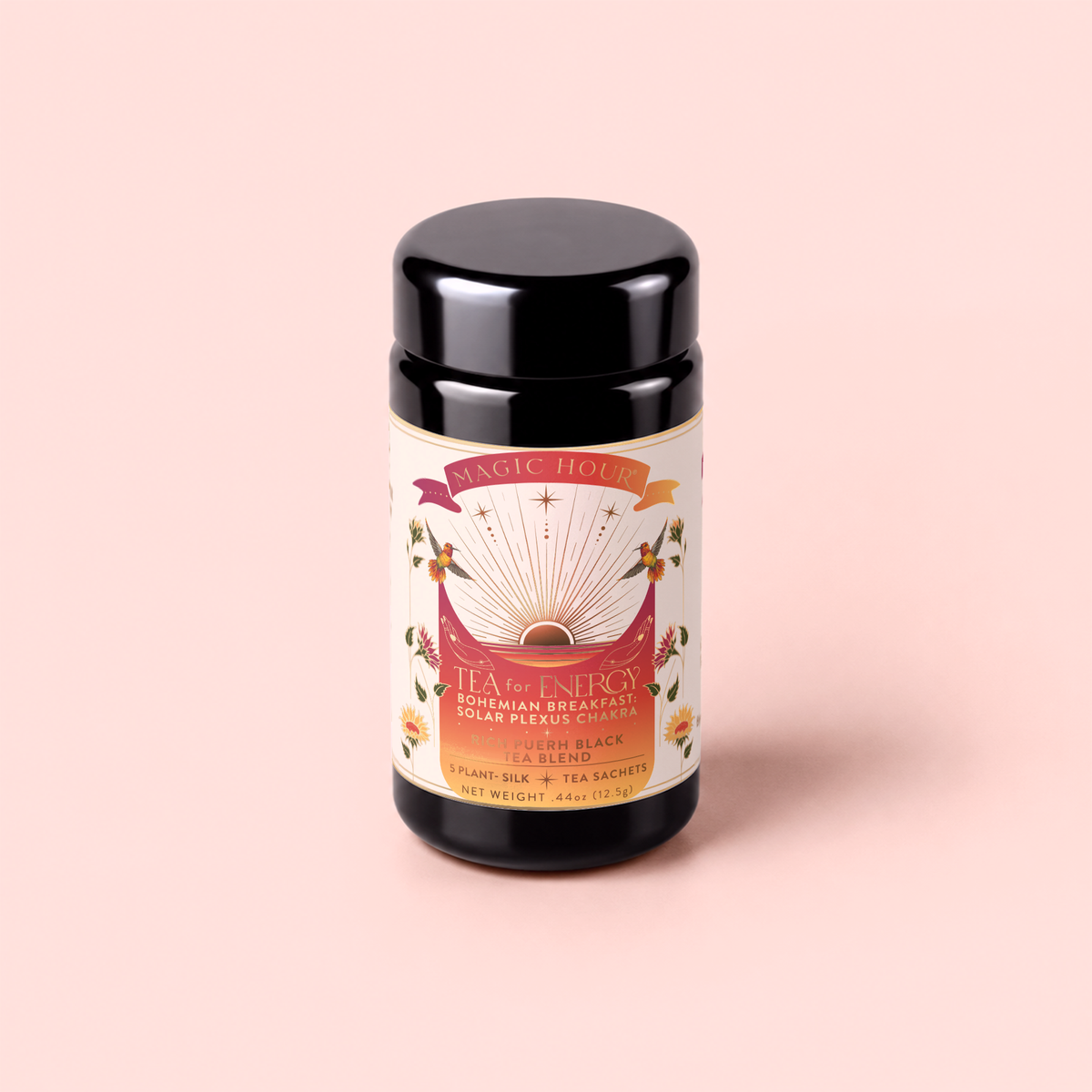 A black tea canister labeled “Tea for Energy: Bohemian Breakfast” from the brand Magic Hour, featuring a sunburst design, floral accents, and a light pink background, with an energizing probiotic-rich puerh black tea blend.