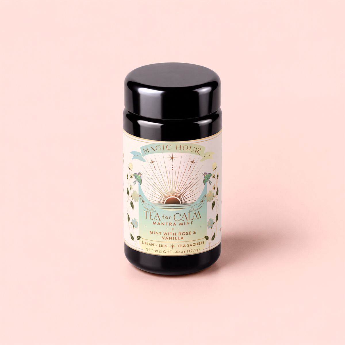A pastel-designed black tea canister labeled “Tea for Calm: Mantra Mint: Mint With Rose & Vanilla Herbal Tea” features green leaves, roses, and a radiating sunburst on a soft pink background—perfect for storing your favorite mint with rose and vanilla herbal tea blends.