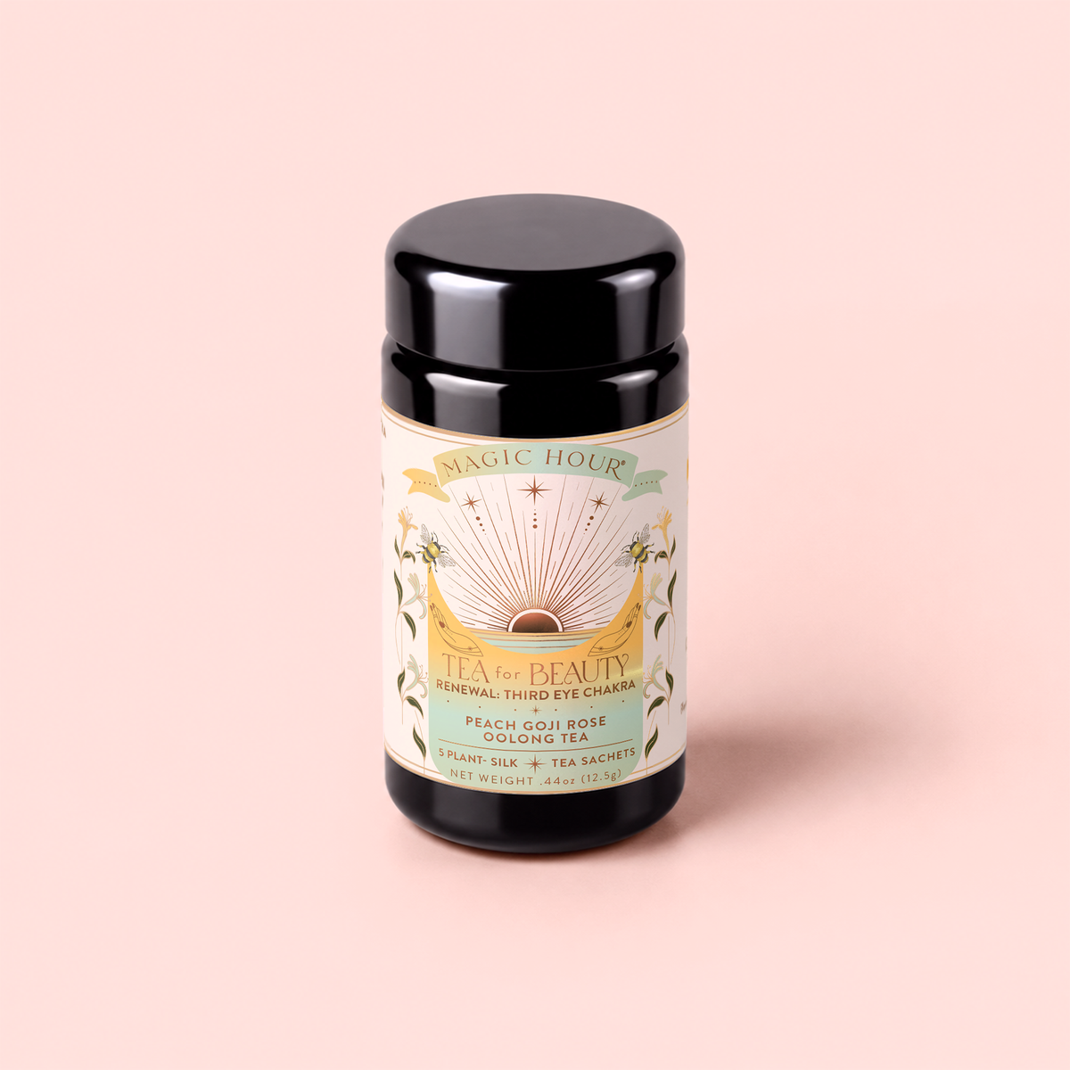 A black canister labeled “Tea for Beauty: Renewal: Peach, Goji & Rose Oolong Tea” sits on a soft pink background, its label adorned with gold accents and decorated with floral and sun illustrations.