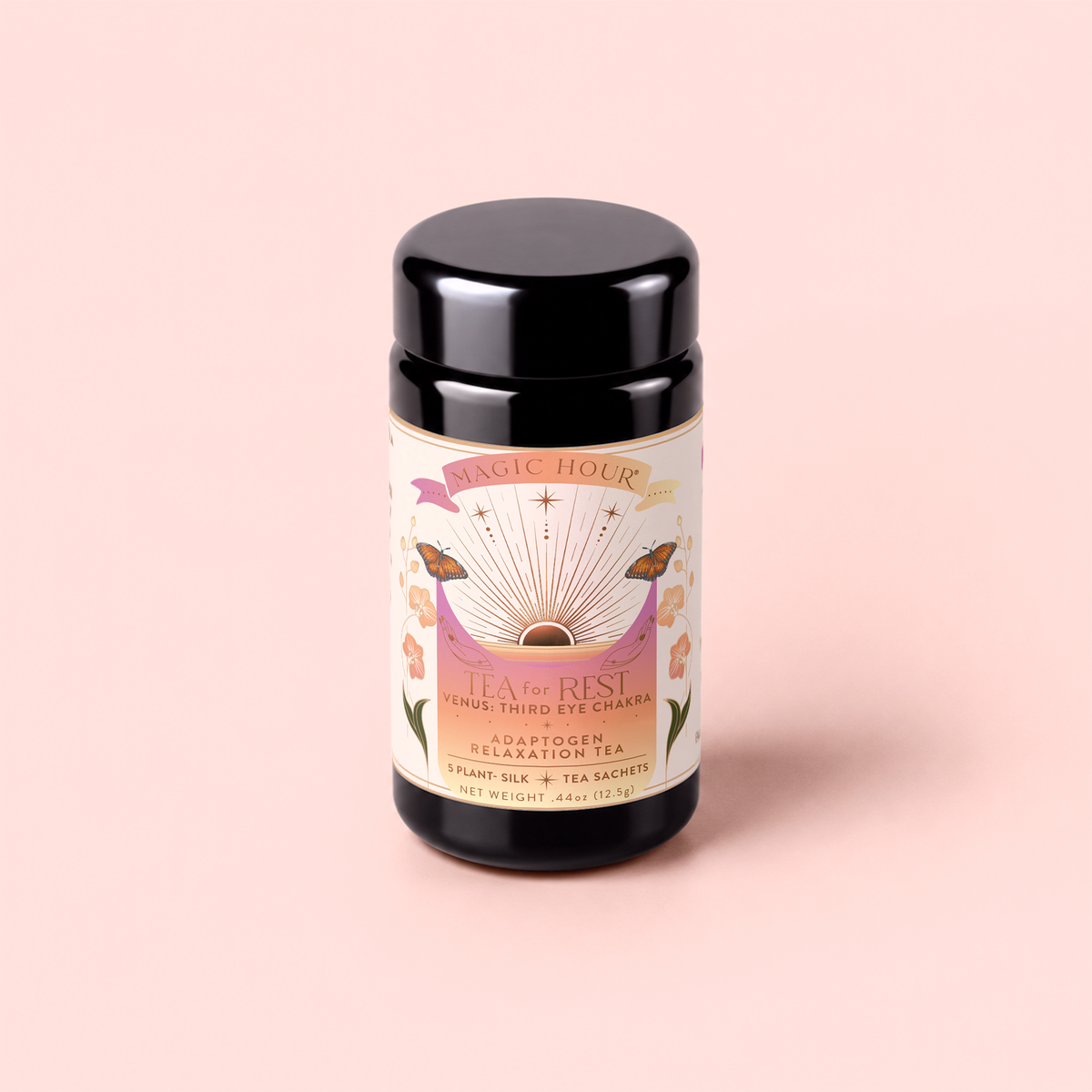 A black tea canister labeled “Tea for Rest: Venus: Mango Blossom & Nervines Herbal Tea” features a vibrant label adorned with flowers, stars, and sun rays, set against a soft pink background. This soothing herbal blend is specially crafted to encourage relaxation while supporting skin hydration and collagen production.