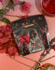 A packet of tea labeled "The Lovers" from Magic Hour is surrounded by red flowers and lavender sprigs on a gradient pink background. A golden tea infuser and a clear cup of red tea with Organic Hibiscus are also positioned nearby. The packet has an intricate, artistic design.