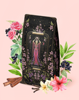 Introducing The Queen of Cups: Hibiscus-Vanilla-Berry Tea for Balance & Heart Health—a beautifully designed tea package featuring the tarot "Queen of Cups" surrounded by flowers, berries, cinnamon sticks, and green leaves on a soft pink background. Perfect for an emotional balance or self-love ritual.