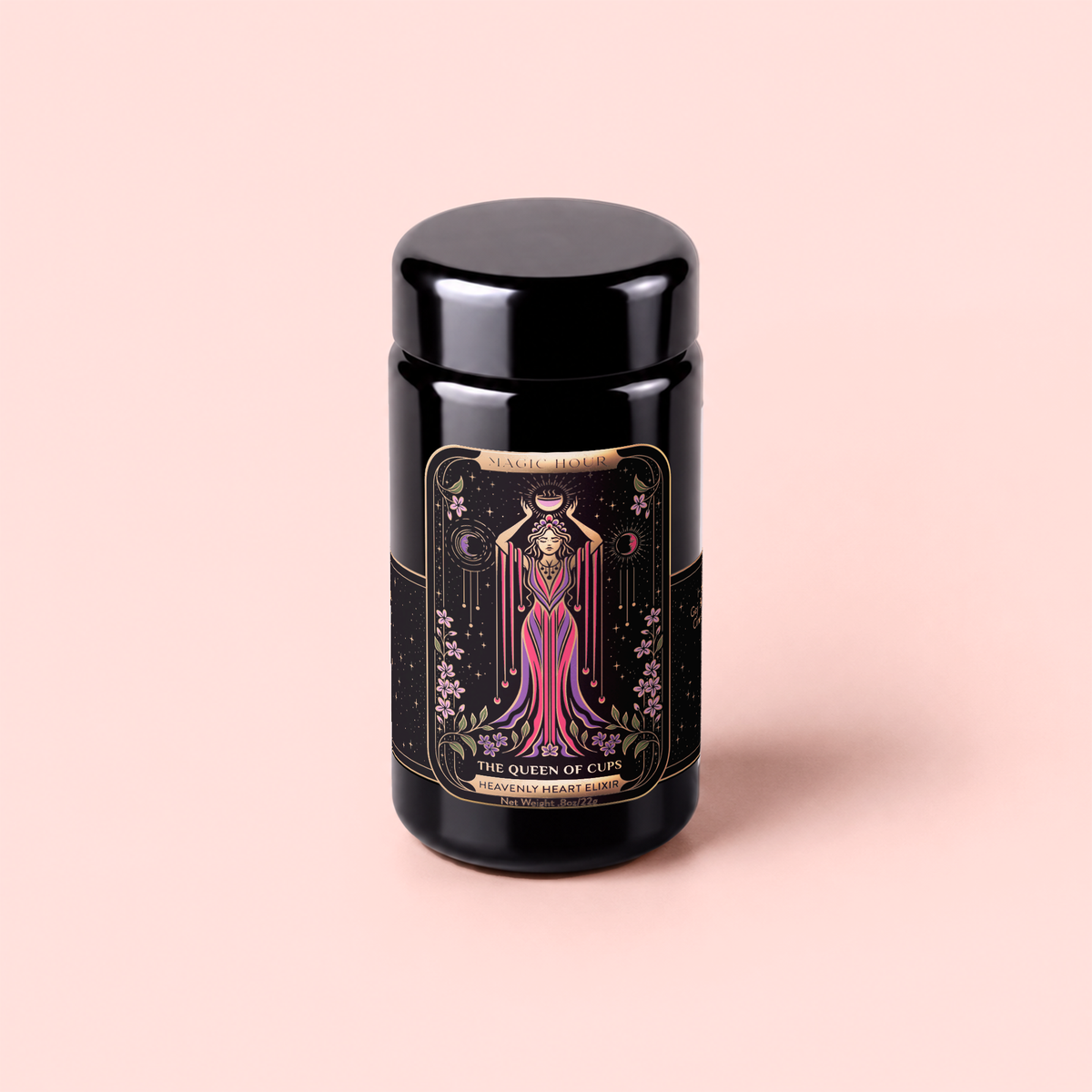 A black jar with a decorative label featuring an illustrated woman in a flowing dress, titled “The Queen of Cups: Hibiscus-Vanilla-Berry Tea for Balance & Heart Health,” sits against a light pink background. This special tea blend is thoughtfully crafted to inspire emotional balance and makes a beautiful addition to any herbal tea collection.
