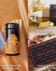 A decorative background highlights the Topaz November Birthstone Mini Gift Set, which features a golden topaz tea traveler jar, a Topaz Wellness Tea branded gift box, an opalite moon tea strainer, and a set of tarot cards, all artfully arranged to celebrate the gem-inspired tea ritual.