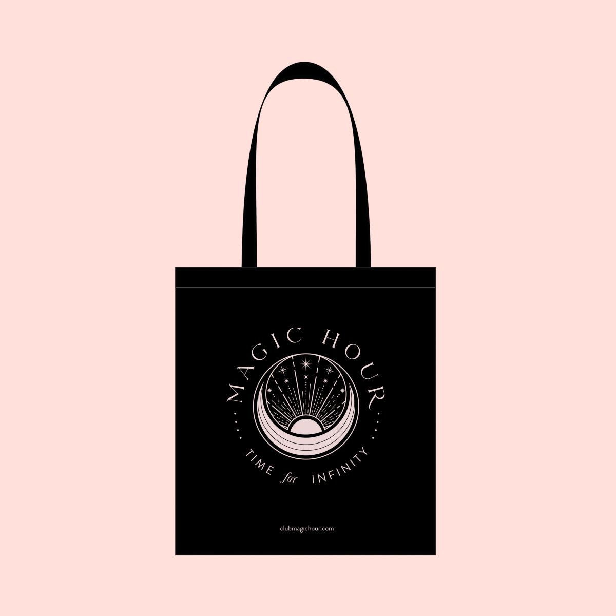 The Magic Hour Tote Bag features a black cotton design with white illustrations and text. It showcases a stylized hourglass at the center, embellished with celestial motifs in metallic gold. The words &quot;Magic Hour&quot; appear at the top, while &quot;Time for Infinity&quot; is displayed below. A soft peach background complements the mystical theme, adding warmth.