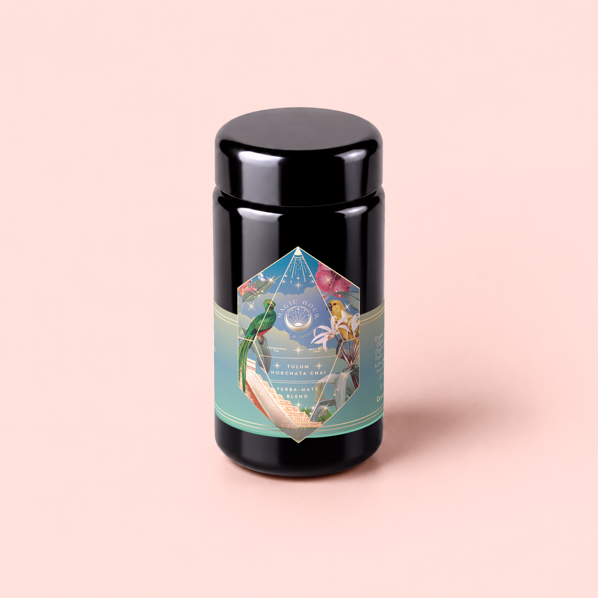 A glossy black jar labeled “Tulum Horchata Chai,” adorned with a vibrant geometric design, botanical illustrations, and gold lettering, set against a pale pink background—an elegant vessel for an adaptogenic wellness potion infused with ashwagandha and yerba mate.