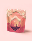 A pink and gold resealable pouch with Middle Eastern geometric patterns and cityscape art, labeled “Turkish Delight,” features a calming, caffeine-free herbal tea blend, set against a soft pink background.