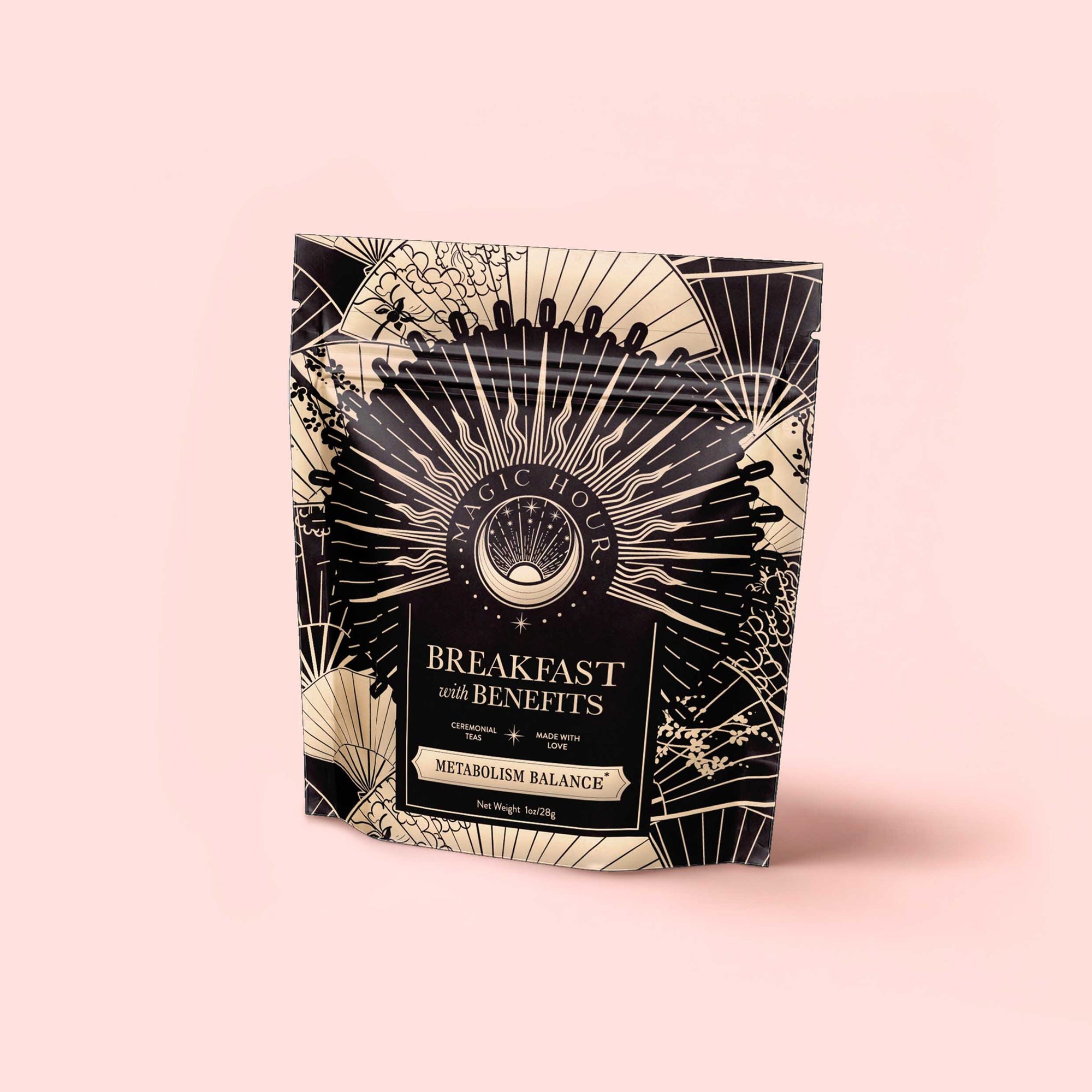 A standing pouch of "Metabolism Balance: Breakfast with Benefits" features an ornate black-and-gold sunburst on light pink—ideal for anyone seeking a metabolism or adaptogen tea to elevate their morning routine.
