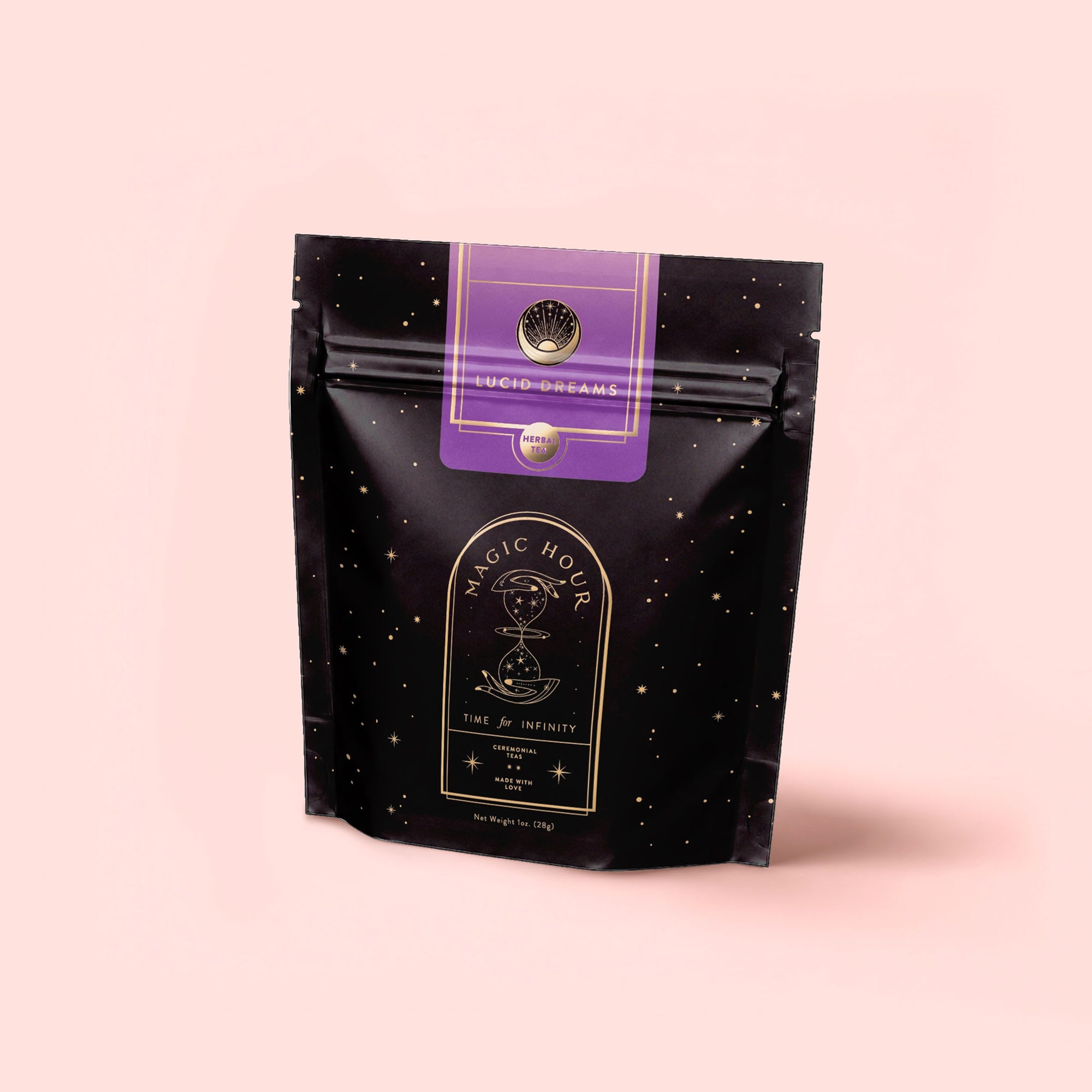 A black resealable pouch with gold stars and "Magic Hour" and "Lucid Dreams" labels sits on a light pink background, evoking a soothing, caffeine-free elixir. Features mystical symbols and elegant fonts for Lucid Dreams: Tulsi-Turmeric Herbal Tea for Sleep & Calm.