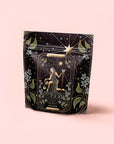 A decorative black pouch features a tarot-inspired illustration of "The Star" and is perfect for storing The Star: Vanilla-Ginger Beauty Potion with Jasmine & Shatavari.