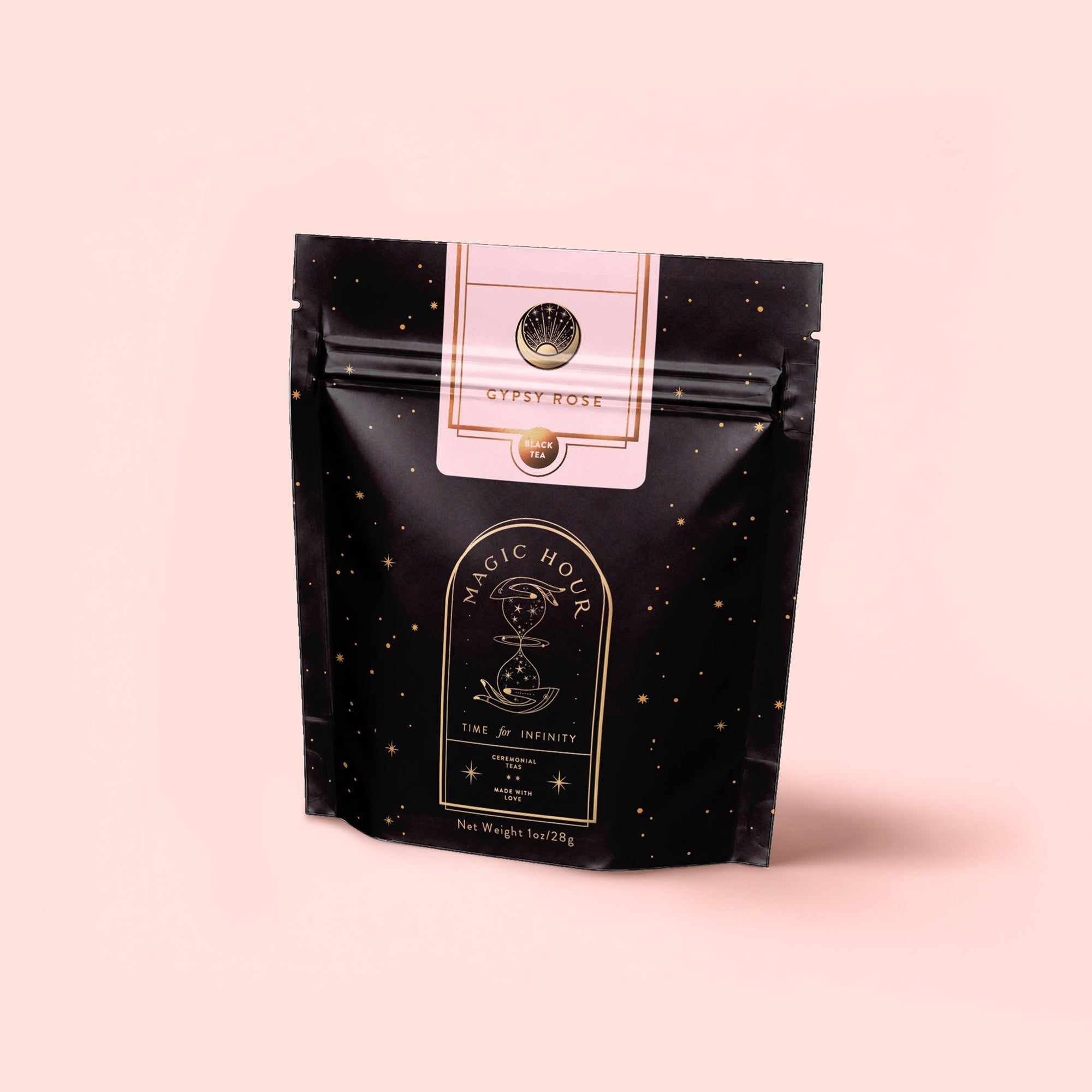 A black, resealable pouch of Magic Hour’s Gypsy Rose Black Tea features gold star patterns, mystical artwork, and a label on a pale pink background, highlighting its biodynamically grown rose tea blend.