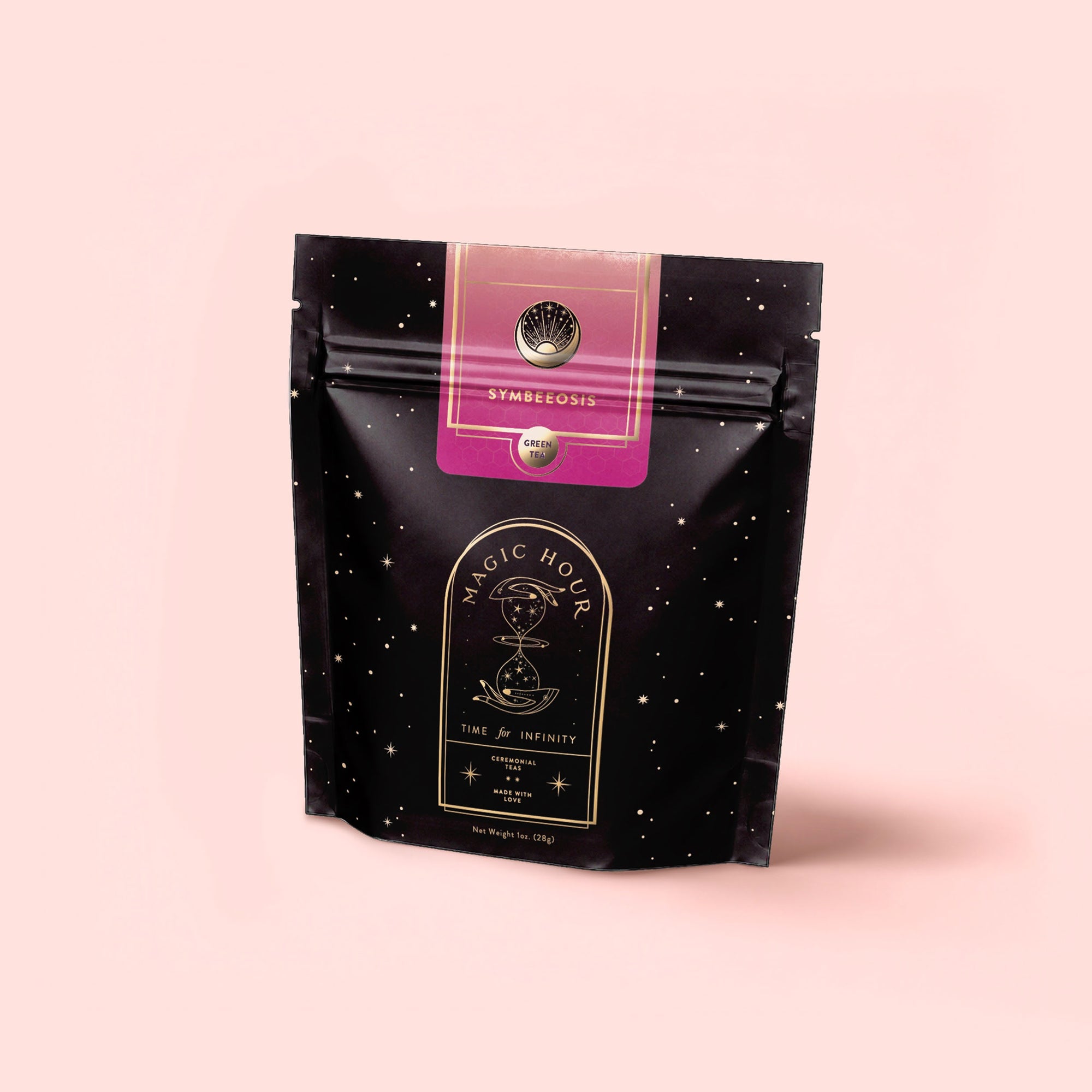 A black resealable tea pouch with star-like dots, labeled "Symbeeosis: Beautifying Immunitea for the Queen Bee," stands on a light pink background, its design hinting at a soothing and beautifying wellness blend inside.