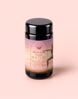 A jar of Vata: Caffeine-Free Saffron-Rose Spice Tea for Inner Beauty Evening sits on a pink background. The label highlights this caffeine-free herbal blend, featuring saffron, rose, and spices, along with the silhouette of a dancing figure. This soothing ashwagandha-infused tea is crafted to promote balance and relaxation.