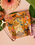A vibrant tea package named "Venus" from Magic Hour, adorned with Art Nouveau-style illustrations of a woman and child surrounded by roses and butterflies, is part of The Best of Winter Box. This exquisite set boasts over 200 cups of winter astrology teas. The collection is beautifully displayed on a floral background alongside a gold tea infuser and fresh flowers.
