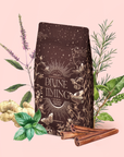 A brown, ornate bag labeled "Divine Timing Vitality" rests among ginger, mint, rosemary, cinnamon sticks, and leafy branches—adaptogenic herbs for natural vitality—set against a soft pink background.