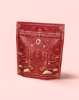 The Year of the Rabbit Carrot Cake Tea comes in a red, resealable pouch featuring gold rabbit, cloud, and celestial designs on light pink—an elegant East Asian-inspired look ideal for Chinese New Year or caffeine-free tea enthusiasts.