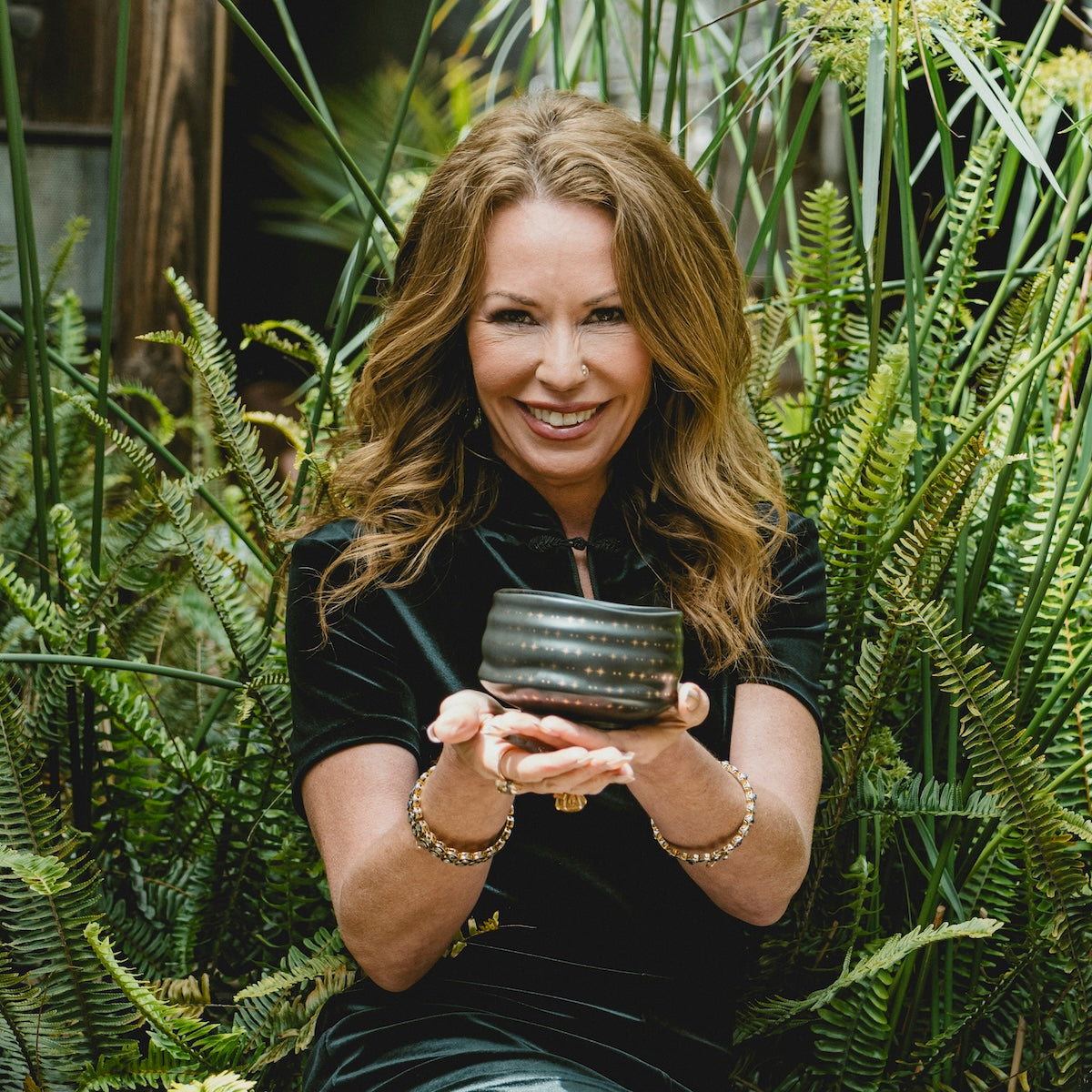 Zhena Muzyka in a garden holding a cup of tea.