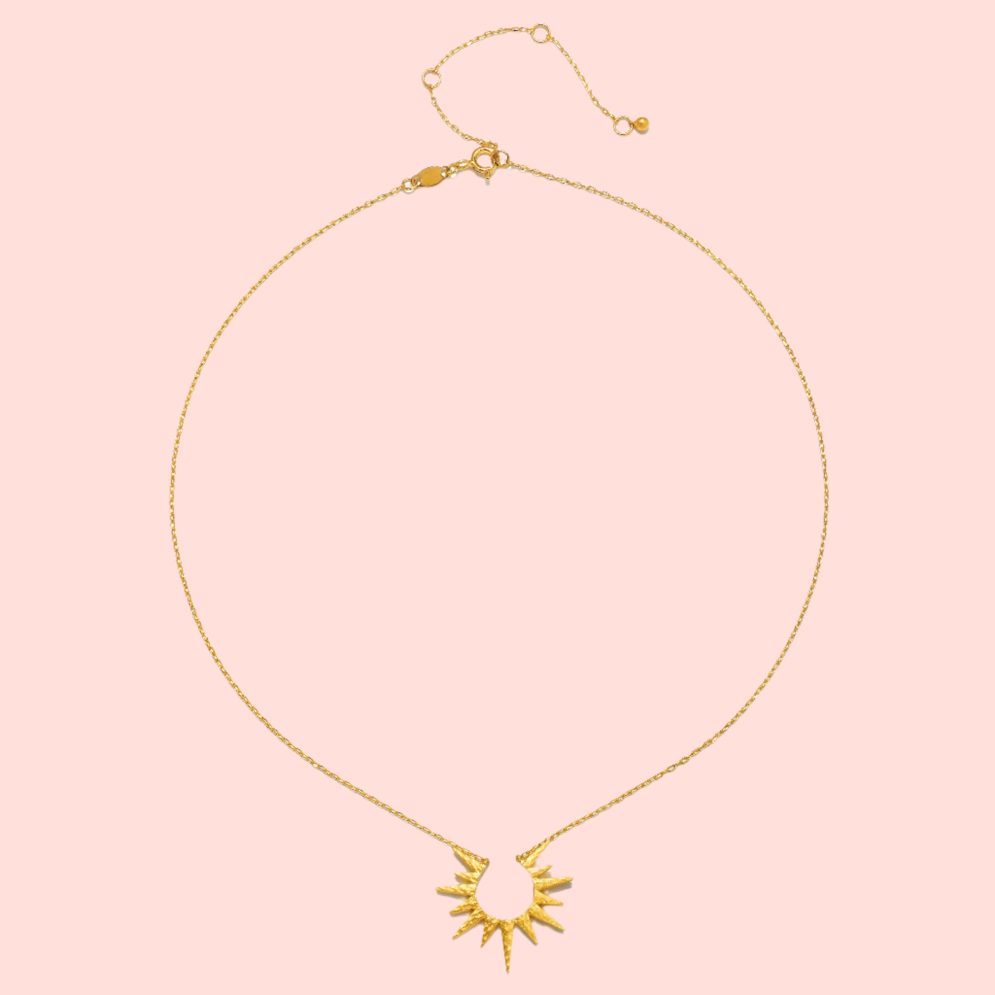The 16" North Star Burst Necklace features an 18kt gold plate, a delicate chain, a sunburst-shaped pendant with pointed rays, an adjustable clasp, and a minimalist design.