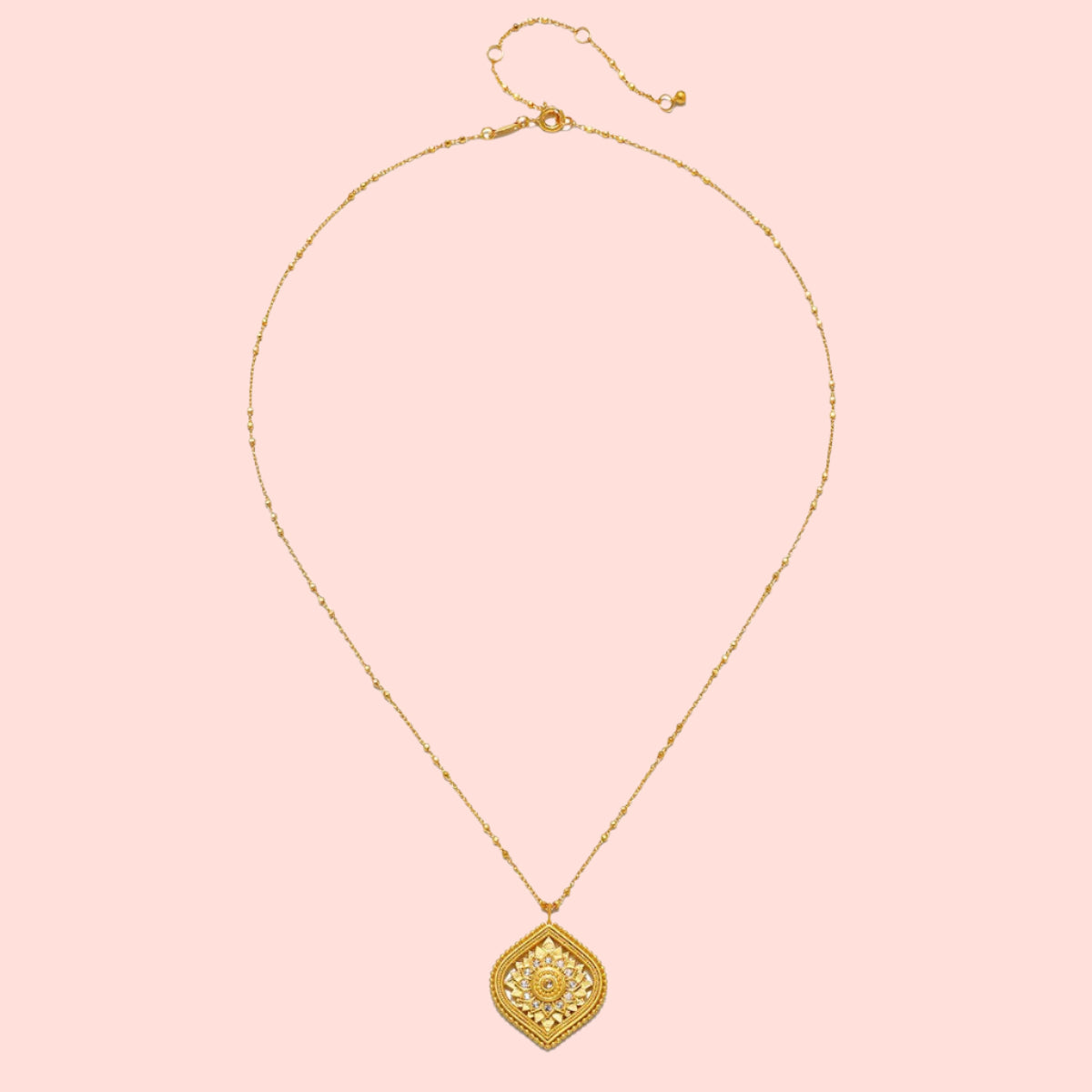 An 18” necklace featuring a delicate gold chain with small beads and a detailed, diamond-shaped white topaz lotus medallion pendant adorned with intricate floral patterns.