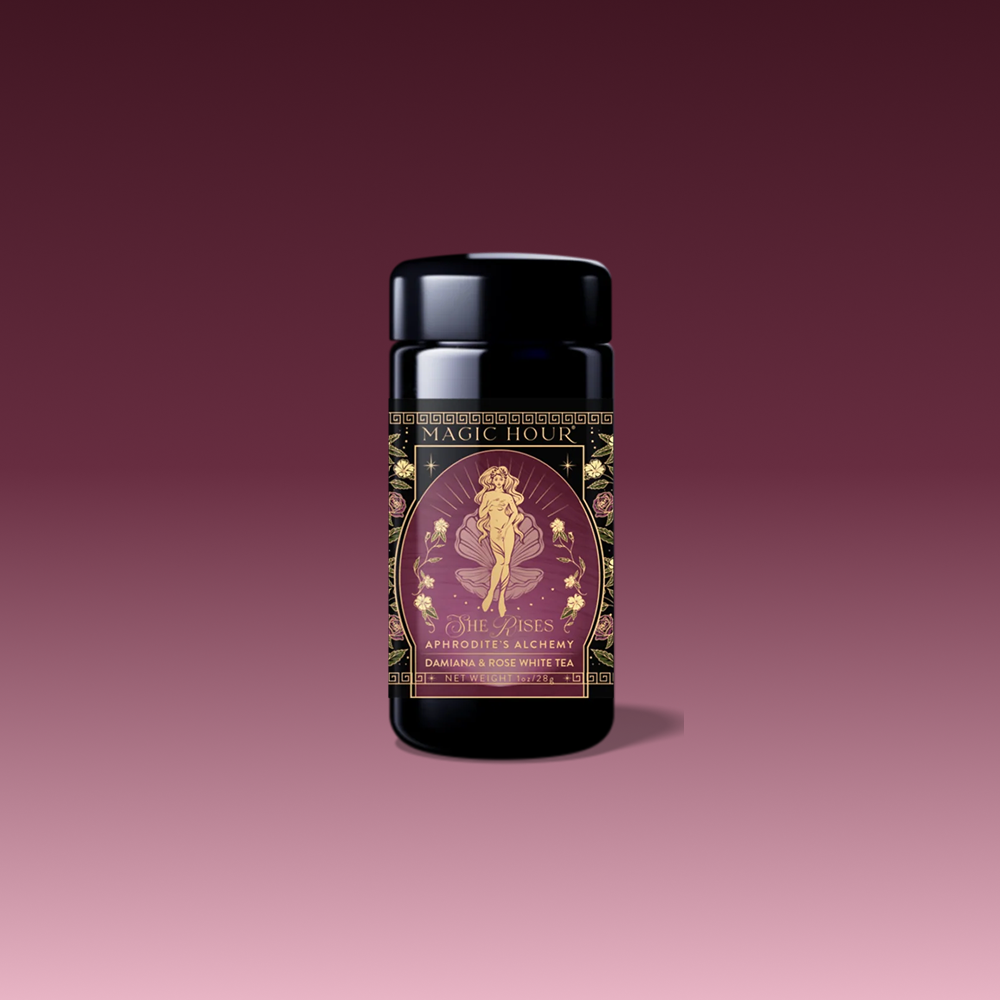 A beautifully designed tea package labeled "Aphrodite's Alchemy: Damiana &amp; Rose White Tea," featuring an illustrated goddess of love from Greek mythology, surrounded by flowers and elegant gold accents.