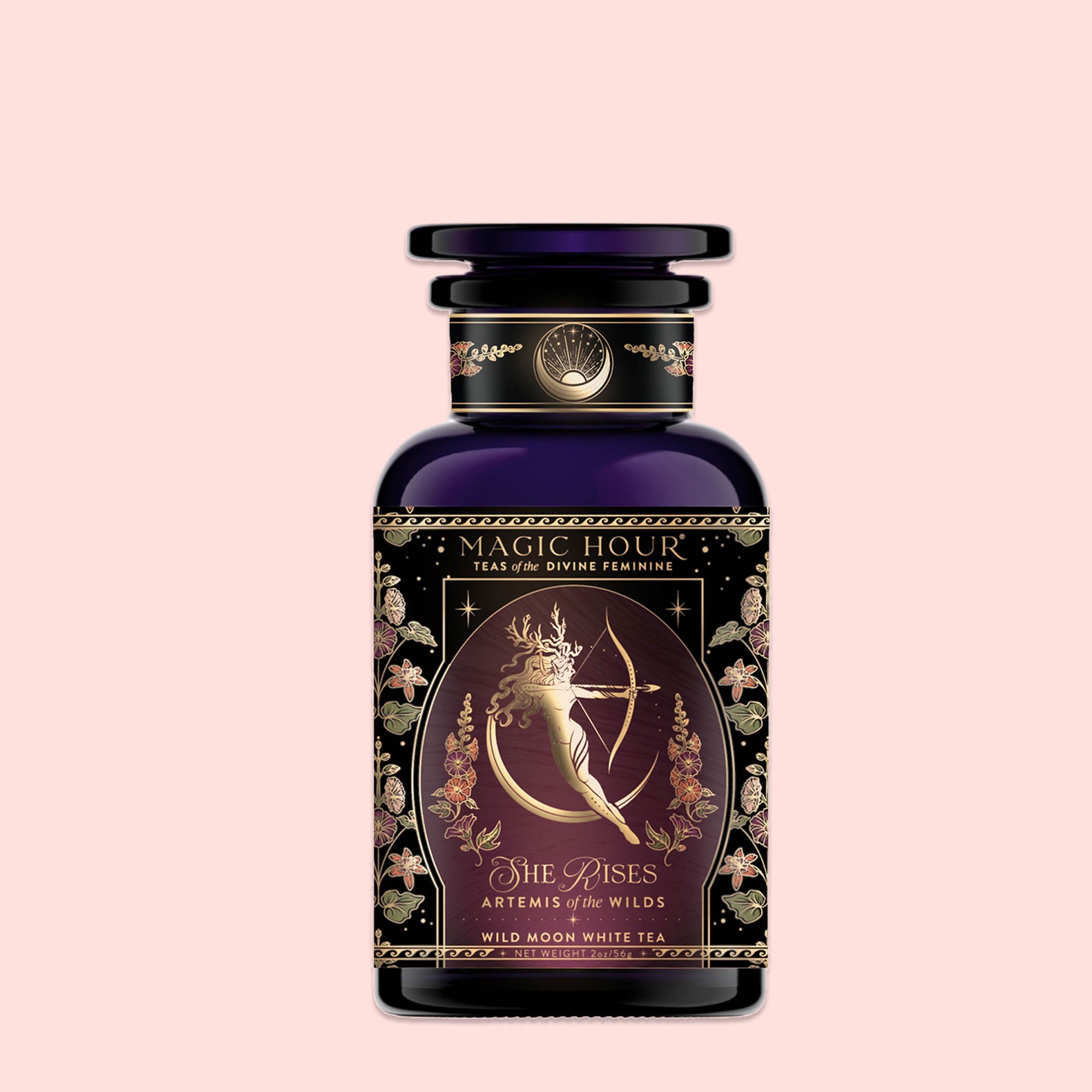 A dark purple glass bottle labeled "Monthly Magic Tea Journey Subscription" features an ornate design with a woman holding a bow and the words "She Rises, Artemis of the Wilds, Wild Moon White Tea," perfect for a goddess ritual.