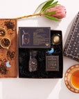 Explore the Scorpio Astrology Tea Gift Set, a heavenly collection that includes a Scorpio-themed tea package with a jar, tea infuser, insightful card, and a magical box on a wooden tray. This set is complemented by a protea flower, two golden spoons filled with loose tea, and a cup nestled in an elegant saucer.