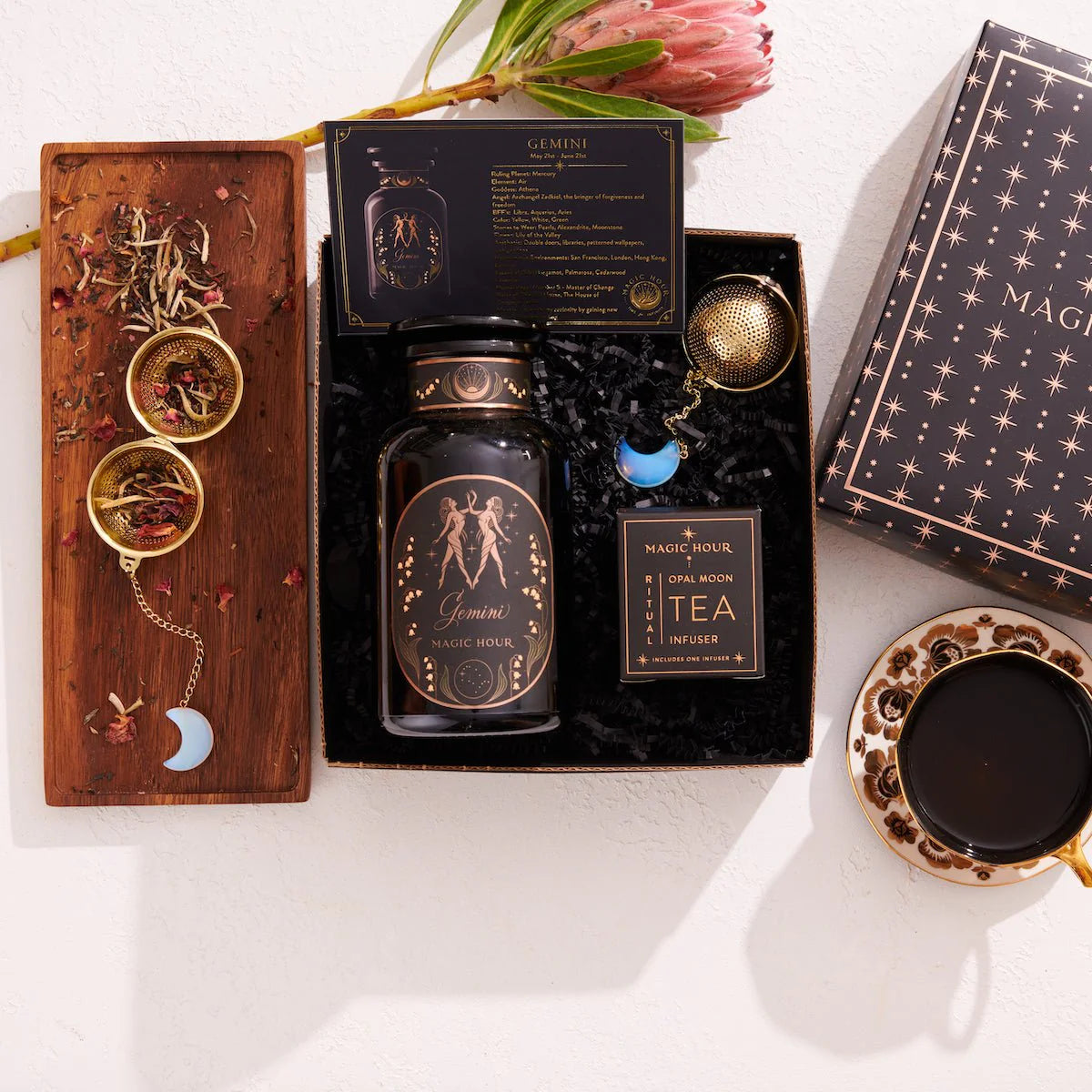 The Gemini Astrology Tea Gift Set offers a luxurious and comforting tea experience with a bottle of "Gemini Magic Hour," complemented by an indulgent blend of botanicals. Nestled on a wooden tray with a tea infuser, card, and dried herbs, it invites you to relax with its celestial charm.