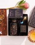 A flat lay showcasing the Libra Astrology Tea Gift Set. This set contains a dark tea jar adorned with floral designs, a box of Moonlight White Tea bags, a large decorative flower, two golden tea infusers, and a cup of tea on a patterned saucer. It also includes a booklet and packaging box to complete the ensemble.