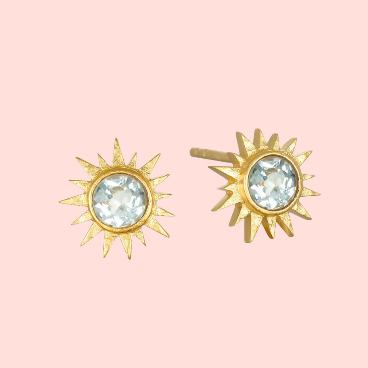 Blue Topaz Starburst Earrings: Gold-plated studs shaped like sunbursts, each with a clear blue topaz gemstone at the center and radiating pointed rays—a timeless piece for star jewelry lovers.