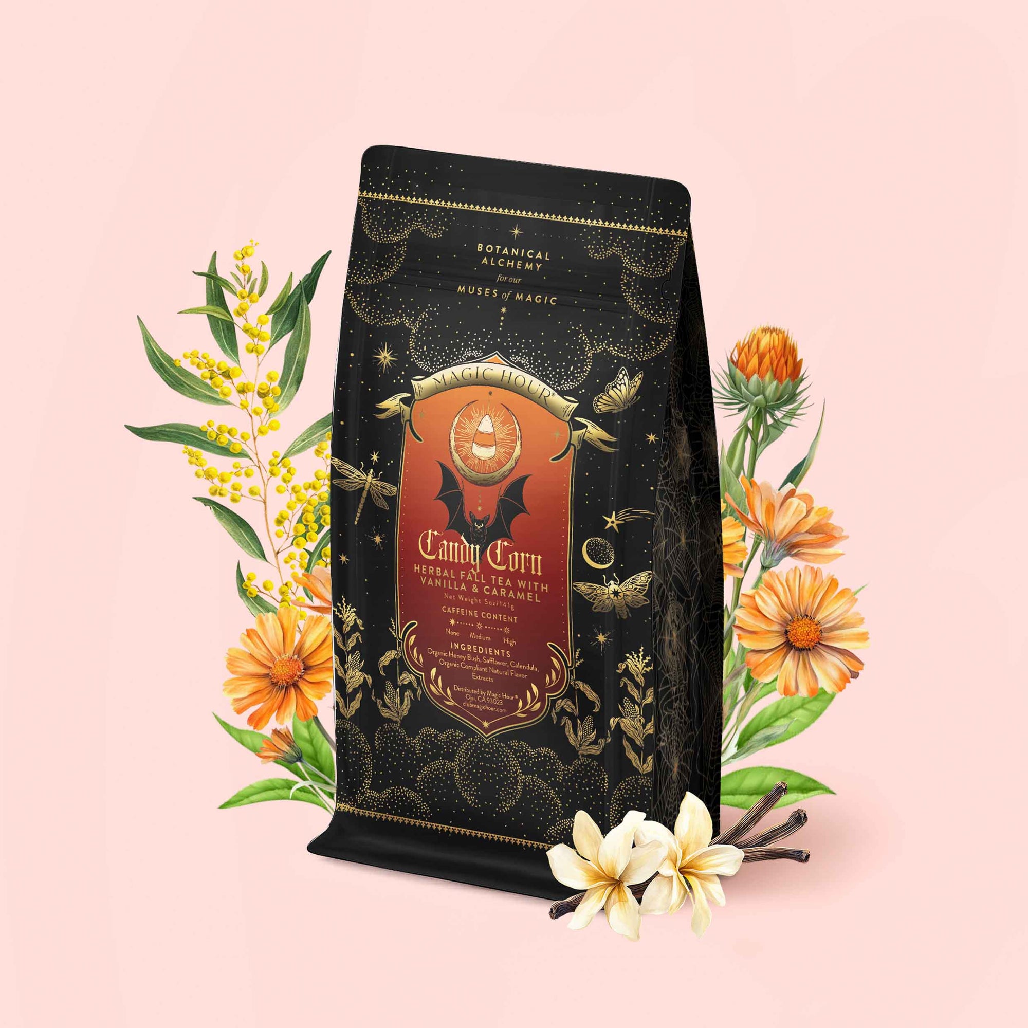 A black and gold tea bag labeled “Candy Corn: Herbal Fall Tea with Vanilla & Caramel”—a delightful caffeine-free blend—is surrounded by yellow flowers, marigolds, and vanilla pods on a light pink background.