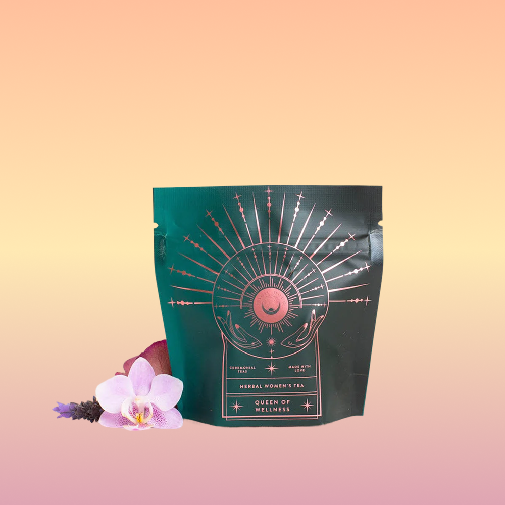 A green tea package with gold celestial designs labeled "Queen of Wellness: Women's Hormone Balancing Tea for PMS, Healthy Cycles & Menopause" is displayed on a peach gradient background, with a pink orchid and purple flower beside it.