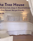 A serene bedroom featuring a double brass bed with white bedding, floral pillows, nightstands with lamps, and soft curtains—ideal for relaxing after The Soul of Tea: A Two Day Retreat in Ojai, CA. Rental details and price: $1,639.