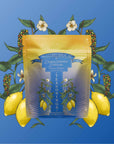 A gold and blue packet labeled “Teasoning: Lemon Pepper Lapsang” sits against a blue background, surrounded by lemons, peppercorns, green leaves, and white flowers—highlighting this smoky citrus botanical seasoning.