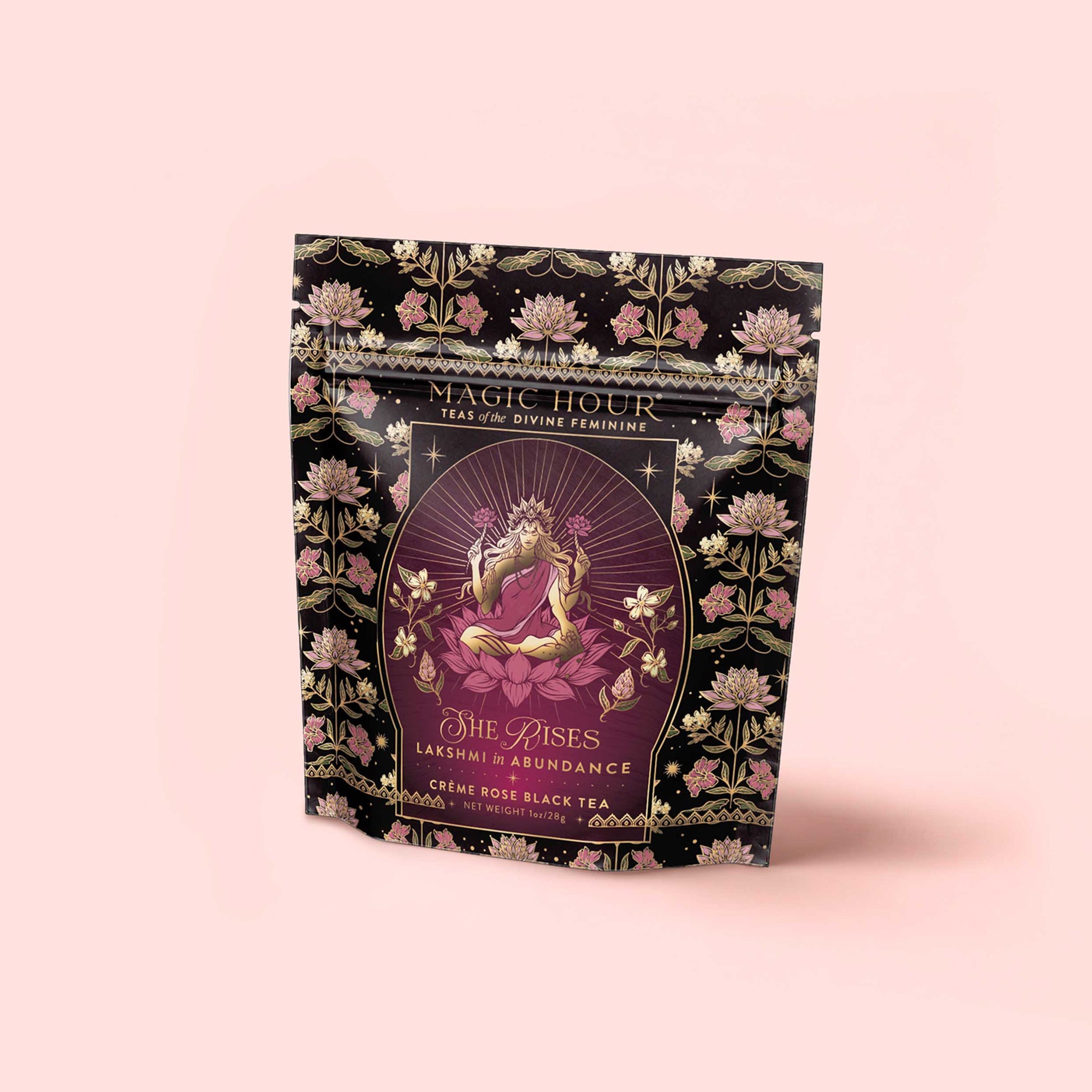 A pink, black, and gold tea package for the “Monthly Magic Tea Journey Subscription” is adorned with a floral design and an illustration of a four-armed woman in lotus pose, labeled “Magic Hour” and “She Rises: Lakshmi Abundance”—an invitation to a goddess ritual tea experience celebrating the Divine Feminine.