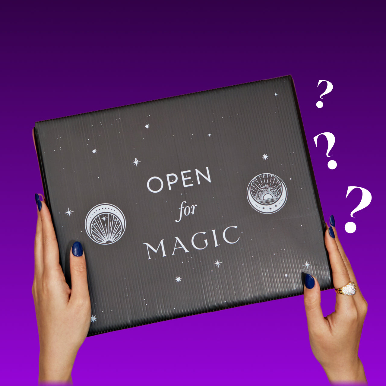 A person with blue painted nails and a ring on their right hand holds a black, rectangular box labeled "OPEN for MAGIC" with celestial illustrations. Two question marks float to the right of The Back to Realitea Mystery Box by Magic Hour, against a purple gradient background.