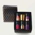 A black and gold gift box labeled "Blissful Black Teas Medley" from Magic Hour contains five small bottles with colored labels, each filled with organic loose leaf tea, and a single gold candle holder. The bottles are arranged in two rows, with two bottles and the holder on the top row and three bottles on the bottom row.
